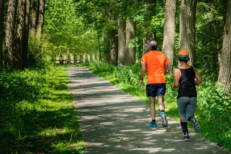 Two runners heading up a tree-lined trail