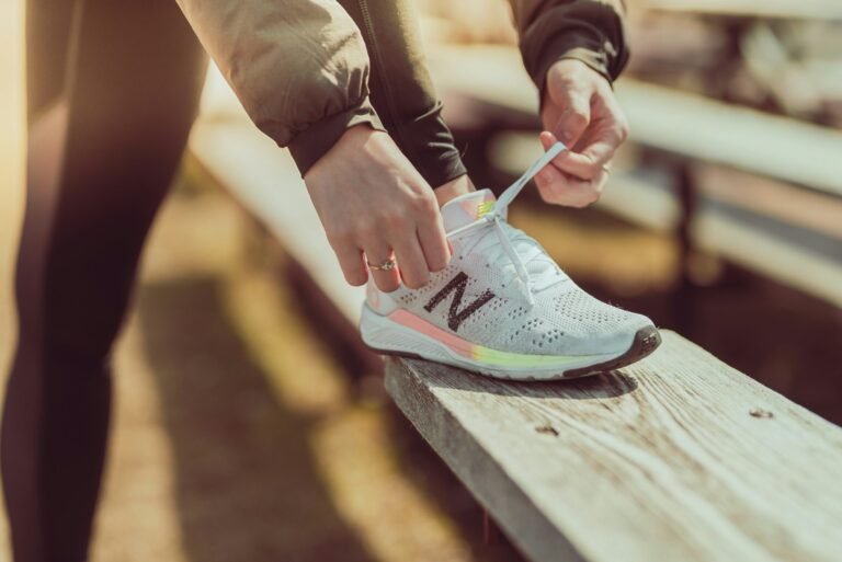 Runner lacing up a running shoe on a wooden rail before a run