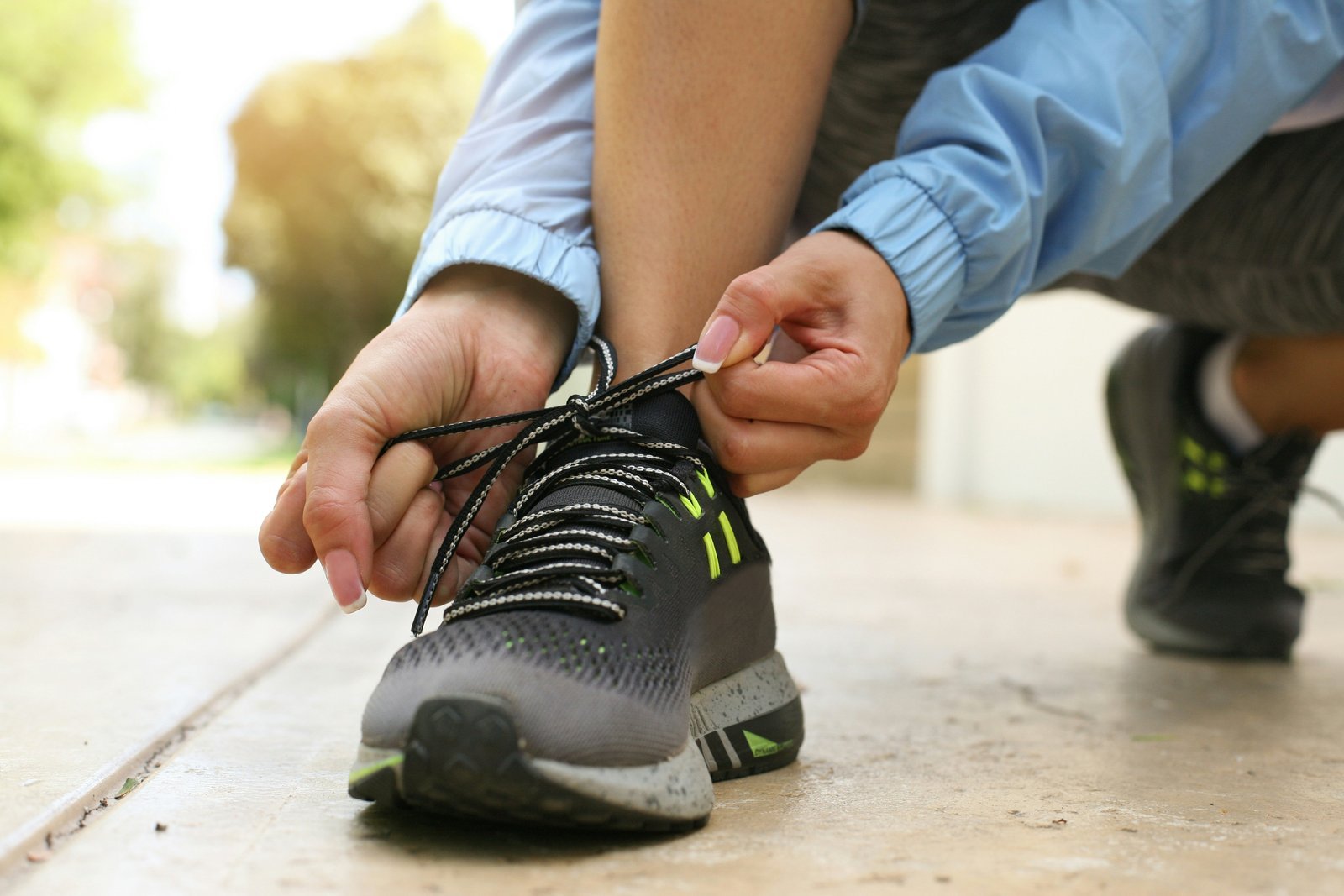 Lacing up a running shoe on the pavement before a run